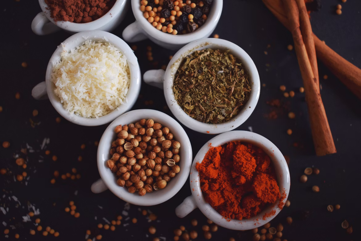 Assorted spices in ceramic bowls with cinnamon sticks